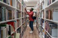 Thoughtful African American student man in glasses choosing book in college library or bookstore Royalty Free Stock Photo