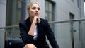 Thoughtful blond businesswoman sitting on bench, problems or stress at work Royalty Free Stock Photo