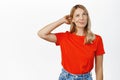 Thoughtful blond girl scratch head and thinking, standing indecisive, confused or clueless, posing against white Royalty Free Stock Photo