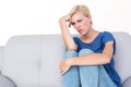 Thoughtful blonde woman sitting on the couch Royalty Free Stock Photo