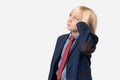 Thoughtful boy with blond hair dressed in blue shirt, red tie and blue jacket standing with hand on chin and looking away isolated Royalty Free Stock Photo