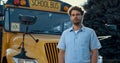 Thoughtful bus driver standing in front yellow vehicle looking camera close up. Royalty Free Stock Photo