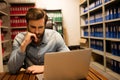 Thoughtful business executive using laptop in file storage room