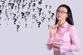 Thoughtful business woman in glasses against the background of a wall with question marks. Decision and doubt concept. Copy space Royalty Free Stock Photo