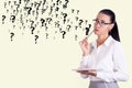 Thoughtful business woman in glasses against the background of a wall with question marks. Decision and doubt concept. Copy space Royalty Free Stock Photo