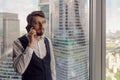 thoughtful businessman with a beard stands next to the window in the office talking Royalty Free Stock Photo