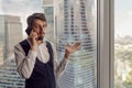 thoughtful businessman with a beard stands next to the window in the office talking Royalty Free Stock Photo