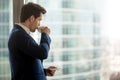 Thoughtful businessman drinking coffee, looking through office w Royalty Free Stock Photo