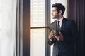 Thoughtful businessman drinking coffee, looking through window at big modern city, having break, deep in thoughts, enjoying view, Royalty Free Stock Photo