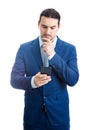 Thoughtful businessman keeps hand under chin, looking at his phone isolated on white background. Reflective business person