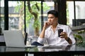 Thoughtful businessman looking at his laptop screen, remote working at a coffee shop Royalty Free Stock Photo