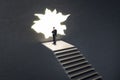 Thoughtful businessman on stairs looking out of hole in broken wall into a bright future. Market research, success, tomorrow and Royalty Free Stock Photo