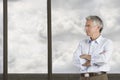 Thoughtful Businessman standing with arms crossed by window