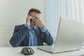 a tired employee at work in front of a computer monitor. Thoughtful businessman talking on the phone. annoying work. A