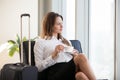 Thoughtful businesswoman drinking coffee with baggage in airport