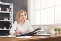 Thoughtful businesswoman reading newspaper at office desktop Royalty Free Stock Photo