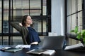 Thoughtful businesswoman relaxing on office chair with hands behind her head and looking through window Royalty Free Stock Photo