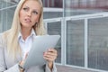 Thoughtful businesswoman using digital tablet while looking away against office building Royalty Free Stock Photo