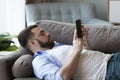 Thoughtful calm lazy smartphone user man chatting online