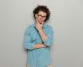 thoughtful casual man with curly hair and glasses touching chin and thinking Royalty Free Stock Photo