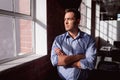 Thoughtful caucasian businessman standing in sunny office with arms crossed looking out of window Royalty Free Stock Photo