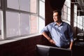 Thoughtful caucasian businessman standing in sunny office looking out of window Royalty Free Stock Photo