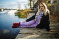 Thoughtful woman sitting on the edge of wooden jetty by the lake with autumn reflections