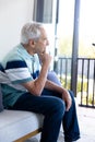 Thoughtful caucasian senior man looking out of the window at home Royalty Free Stock Photo