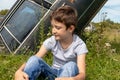 Thoughtful caucasian teenage boy sitting on the grass in countyside in summer day with serious face expression, a retro car is on Royalty Free Stock Photo