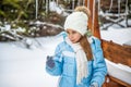 A girl in winter clothes licks a cold icicle while standing in the forest Royalty Free Stock Photo