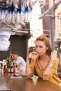 Calm young woman thoughtfully drinking while sitting at the bar counter