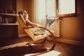 Thoughtful concept. Sad woman lost in thought lounging in comfortable modern chair looking at window in livingroom. Warm natural l