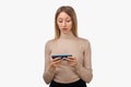 Thoughtful confused young blond woman holding her smart phone. Technology, youth and communication concept Royalty Free Stock Photo