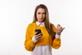 Thoughtful confused young brunette woman holding her smart phone. Technology, youth and communication concept Royalty Free Stock Photo