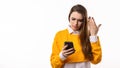 Thoughtful confused young brunette woman holding her smart phone. Technology, youth and communication concept Royalty Free Stock Photo