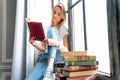 Thoughtful depressed, alone young woman looking out of window pondering on idea and plot of new bestseller of favorite author Royalty Free Stock Photo