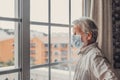 Thoughtful depressed old man looking out of window with hope, thinking over business lockdown loss, future vision after epidemic Royalty Free Stock Photo