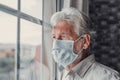 Thoughtful depressed old man looking out of window with hope, thinking over business lockdown loss, future vision after epidemic Royalty Free Stock Photo