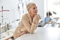 Thoughtful dressmaker in jacket leans onto cutting table in sewing workshop