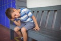 Thoughtful elementary boy sitting on bench