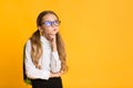 Thoughtful Elementary Schoolgirl Thinking Standing Over Yellow Background