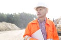 Thoughtful engineer holding clipboard against clear sky