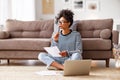 Thoughtful ethnic woman doing paperwork at home