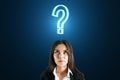 Thoughtful face of a businesswoman closeup and a sign of question over her head on a dark blue background, doubt and decision Royalty Free Stock Photo