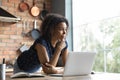 Thoughtful female African American remote employee standing by computer