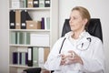 Thoughtful Female Doctor on a Chair Holding a Cup Royalty Free Stock Photo