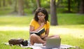 Thoughtful female student with laptop and notebook studying online at park Royalty Free Stock Photo