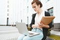 Thoughtful female student sits in park near university and prepares for exams