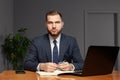 Thoughtful focused clever businessman holding pen with hands wearing suit working on deadline project using laptop indoor Royalty Free Stock Photo