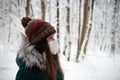 Thoughtful Gaze: Woman in a Mask Amidst a Snowy Forest